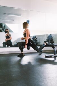 how to do squats - woman in black sports bra and black leggings doing exercise