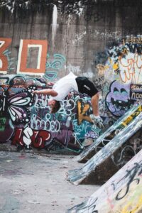 how to do a backflip - man in white t-shirt and black shorts riding skateboard