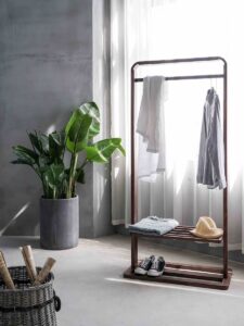 how to be a minimalist - gray dress shirt hang on brown wooden rack in front of window with white curtain