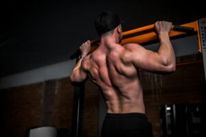 topless man in black shorts holding orange bar